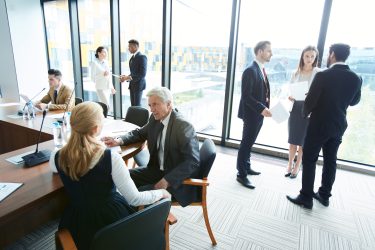 Large group of business people in formalwear discussing work issues in spacious conference room and being in different place of room